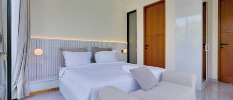 A modern bedroom with a large bed, a sofa, and two wooden doors.