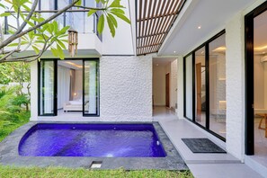 Une maison moderne dotée d’une piscine, de grandes fenêtres et d’un jardin bien entretenu.