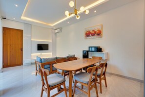Un comedor moderno con una mesa y sillas de madera, un televisor de pantalla plana montado en la pared y una lámpara en el techo.