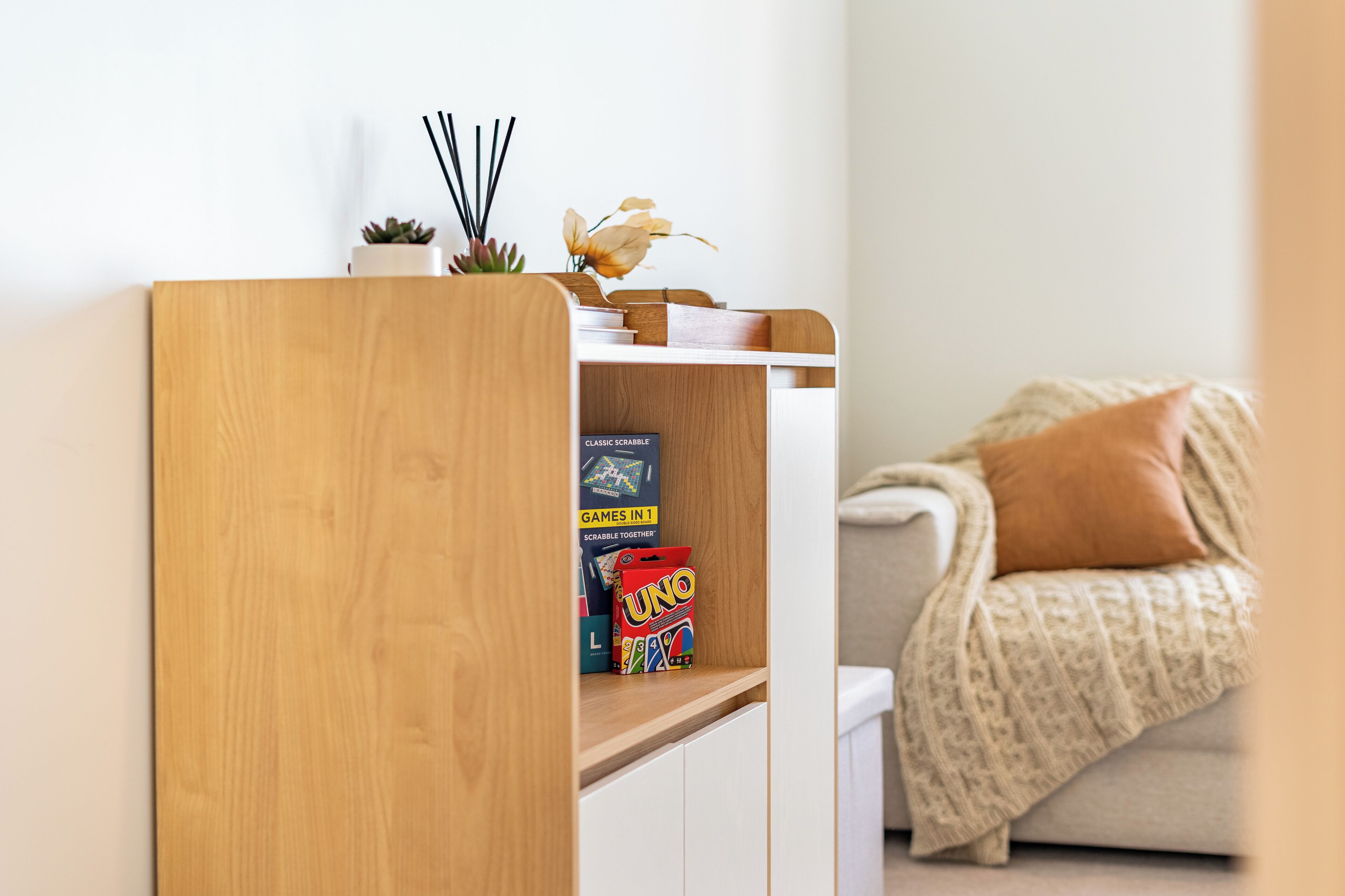 A wooden bookshelf with books and a UNO game box.