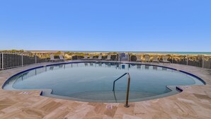 A circular pool with a metal railing, surrounded by a tiled deck and a metal fence. - Experience oceanfront luxury at 32 Ocean Place, a cozy 2-bedroom condo in Fernandina Beach. (Fernandina Beach)