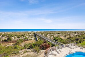 Vistes costaneres amb una passera de fusta que condueix a una zona de piscina.
