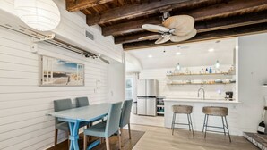 A modern kitchen with white cabinets, a central island, and bar stools. - Charming 3BR home in Fernandina Beach with wooded views and space for 8! (Fernandina Beach)