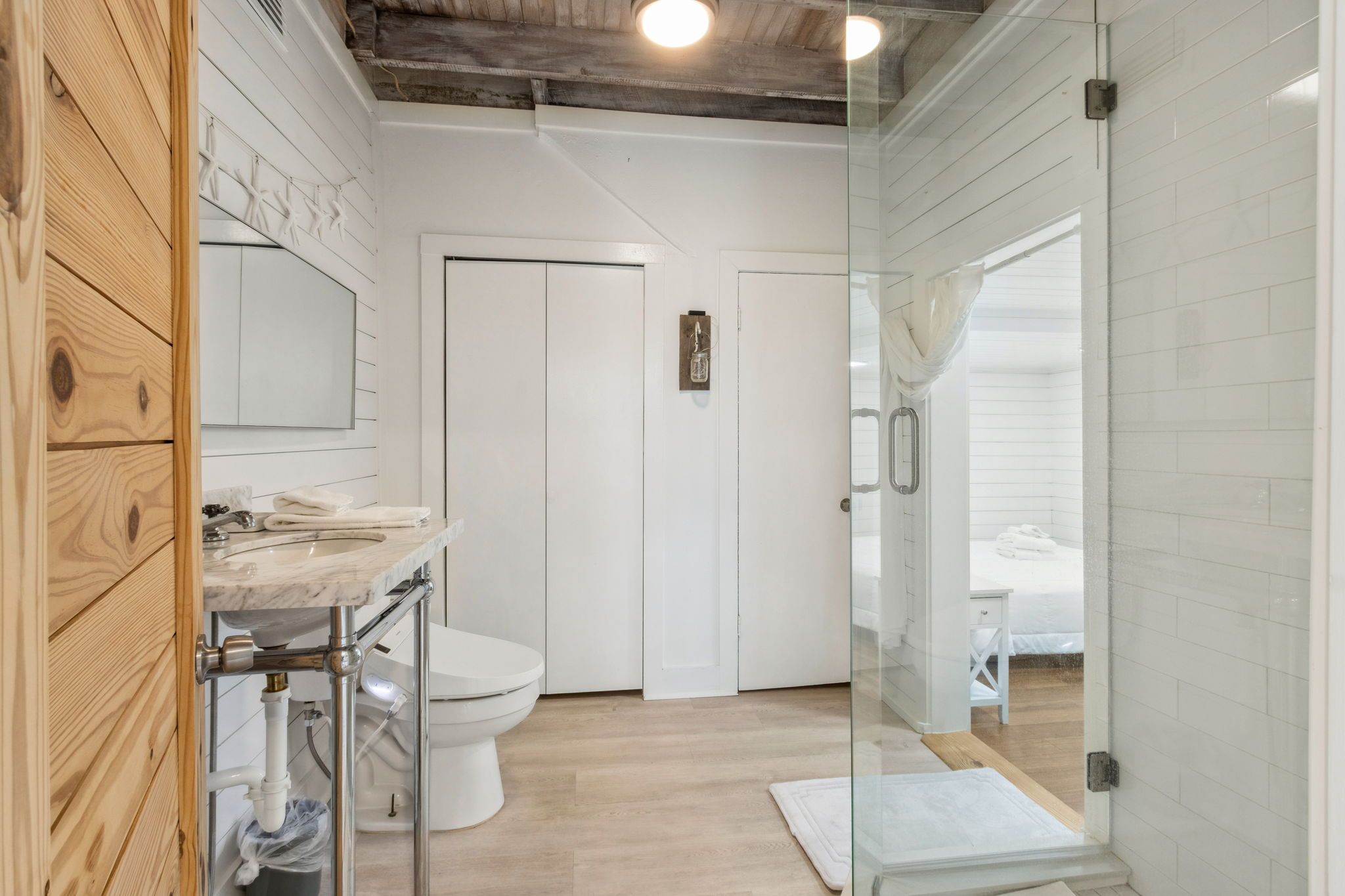 Een moderne badkamer met een houten wastafelmeubel, een douchecabine met glazen wanden en een wit toilet.