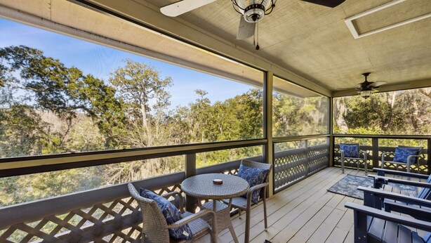 An outdoor deck with wicker furniture, a round table, and a ceiling fan.