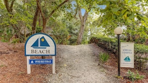 A sign for 'Beach' with a 'Owner Bike Storage' sign below it, and a welcome sign for 'Amelia Landings Condominium Resort Community'.