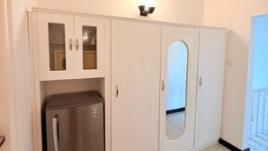 Una cocina con armarios blancos, un refrigerador y una lámpara fijada a la pared.