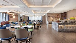 Un espace repas moderne doté de plusieurs tables et chaises, d’un comptoir en marbre et d’un mur décoratif agrémenté d’une horloge et d’un menu.