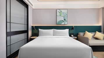 Una habitación de hotel moderna con una cama grande, un sofá y una obra de arte colgada en la pared.