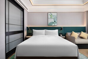 Ein modernes Hotelzimmer mit einem großen Bett, einer Sitzecke und einem Wandbild.