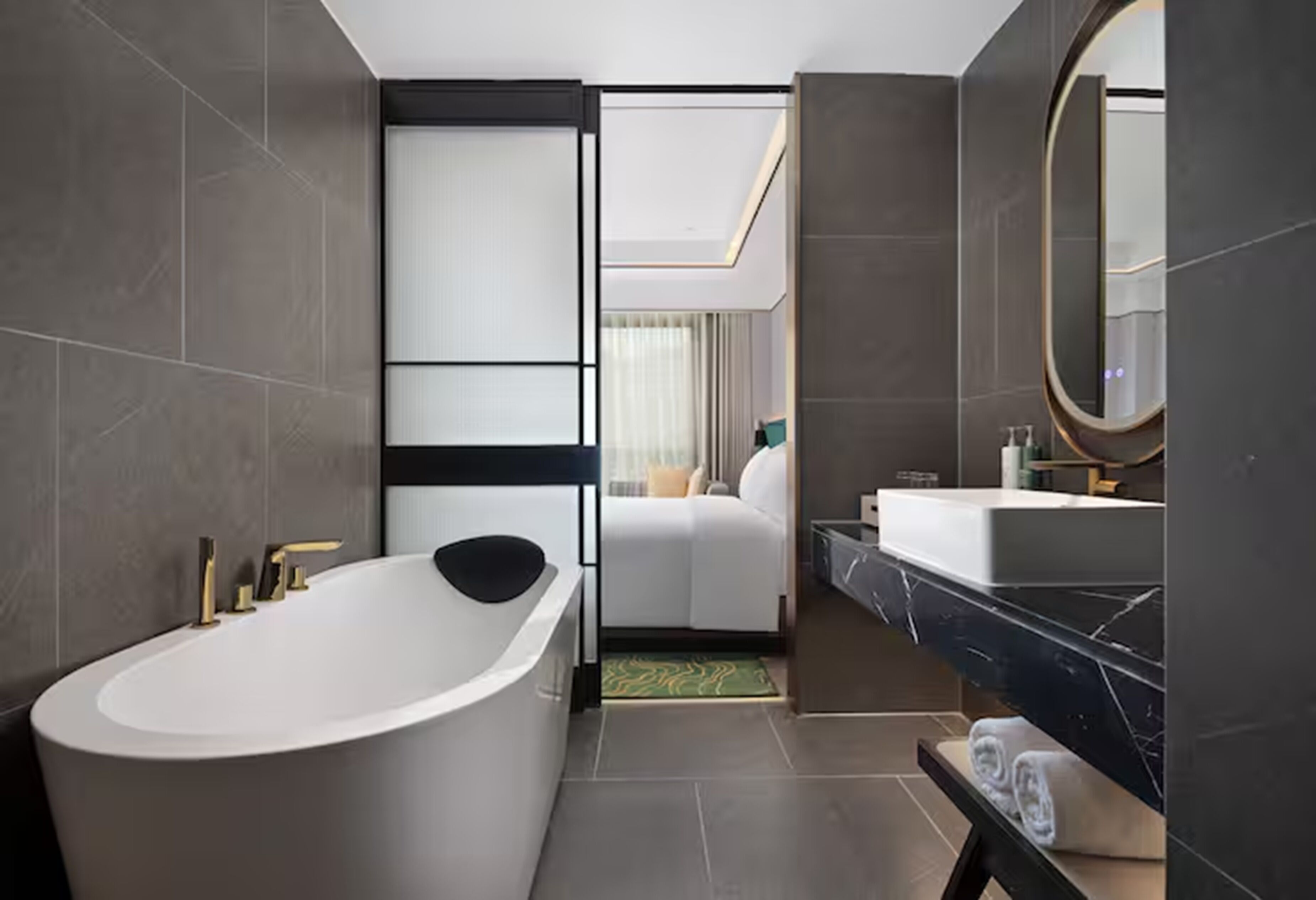 Un baño moderno con una bañera independiente, un espejo grande y una zona separada para el lavamanos.