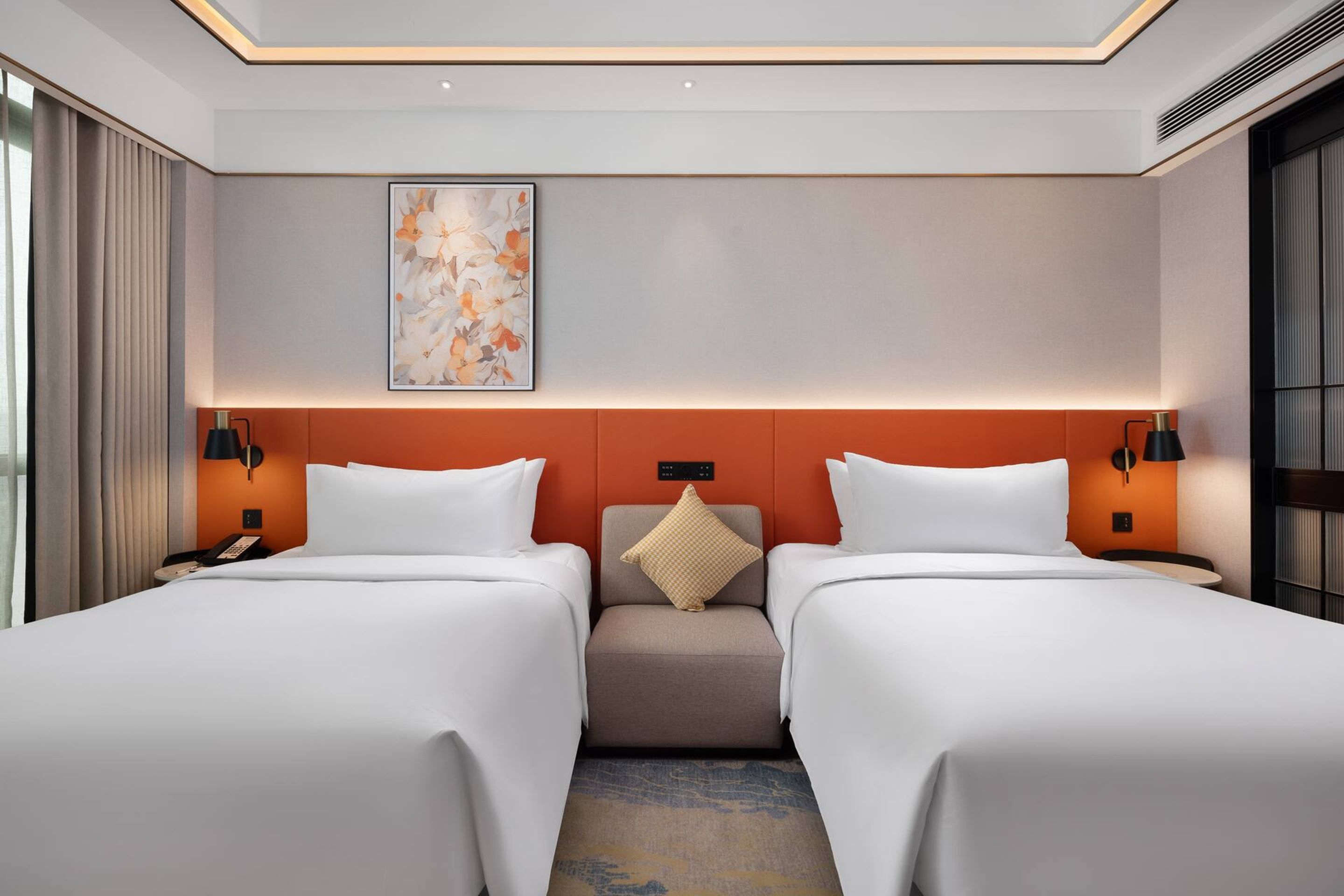 A hotel room with two beds, a neutral color scheme, a decorative wall piece, and a small seating area.