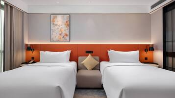 A hotel room with two beds, a neutral color scheme, a decorative wall piece, and a small seating area.