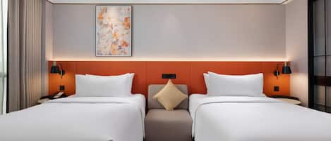 Habitación de hotel con dos camas, una paleta de colores neutros, un elemento decorativo en la pared y una pequeña zona de estar.