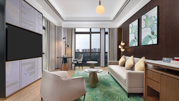 Un salon moderne comprenant un canapé, un fauteuil et une table basse, un téléviseur à écran plat et des œuvres d’art accrochées aux murs.