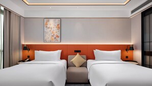 A hotel room with two beds, a neutral color scheme, a decorative wall piece, and a small seating area. - Hilton Garden Inn Leshan Shizhong (Leshan)