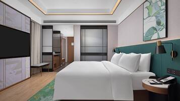 A modern hotel room with a large bed, a desk with a telephone, a TV, and a painting on the wall.