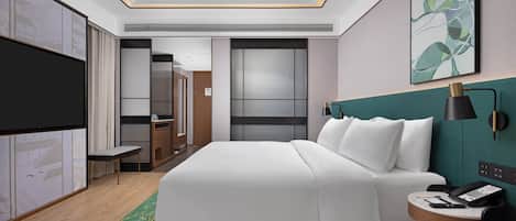 A modern hotel room with a large bed, a desk with a telephone, a TV, and a painting on the wall.
