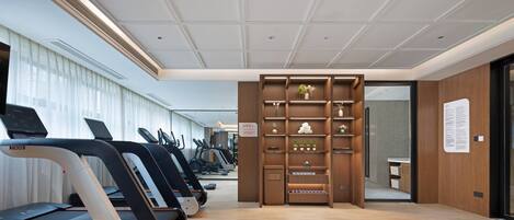 A modern gym with treadmills, a wooden wall unit with plants, and a clean, well-lit interior.