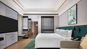 Une chambre d’hôtel moderne équipée d’un grand lit, d’un canapé, d’un bureau et d’une télévision.