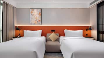 A hotel room with two beds, a neutral color scheme, a decorative wall piece, and a small seating area.