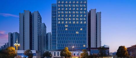 Un hotel de gran altura con un letrero llamativo en la parte superior, rodeado de otros edificios y árboles.