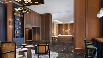 A modern lobby with a reception desk, seating area, and decorative lighting.