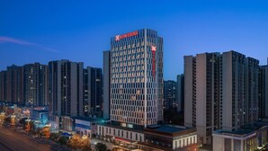 Un hôtel de grande hauteur, doté d’une façade moderne en verre, entouré d’autres immeubles imposants.