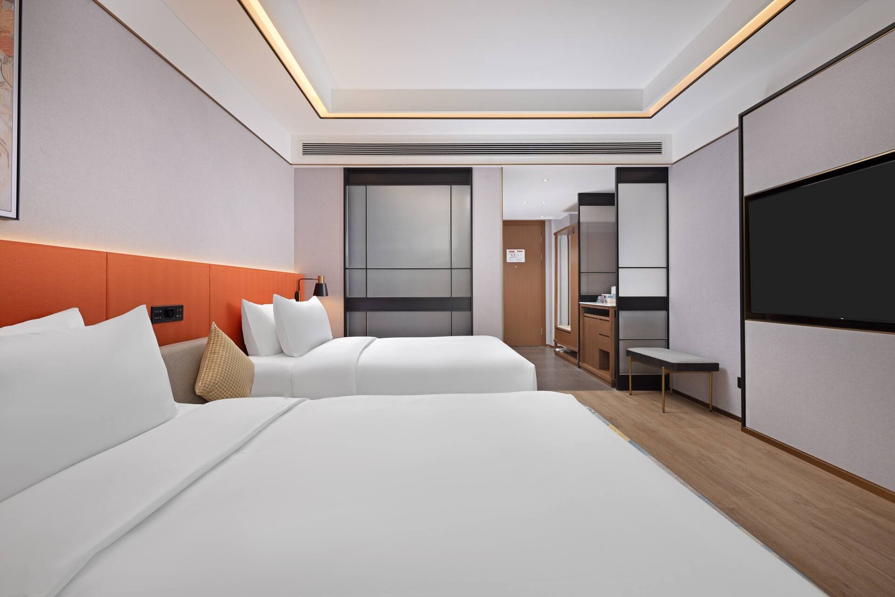 Une chambre d’hôtel avec deux lits, une télévision, un bureau et une salle de bain que l’on aperçoit à l’arrière-plan.