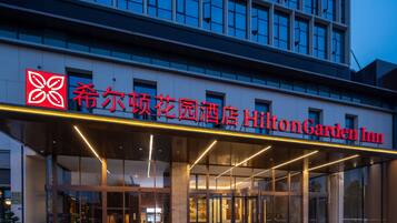 The exterior of Hilton Garden Inn with a modern facade, large glass entrance, and prominent signage.