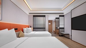 Une chambre d’hôtel avec deux lits, une télévision, un bureau et une salle de bain que l’on aperçoit à l’arrière-plan.