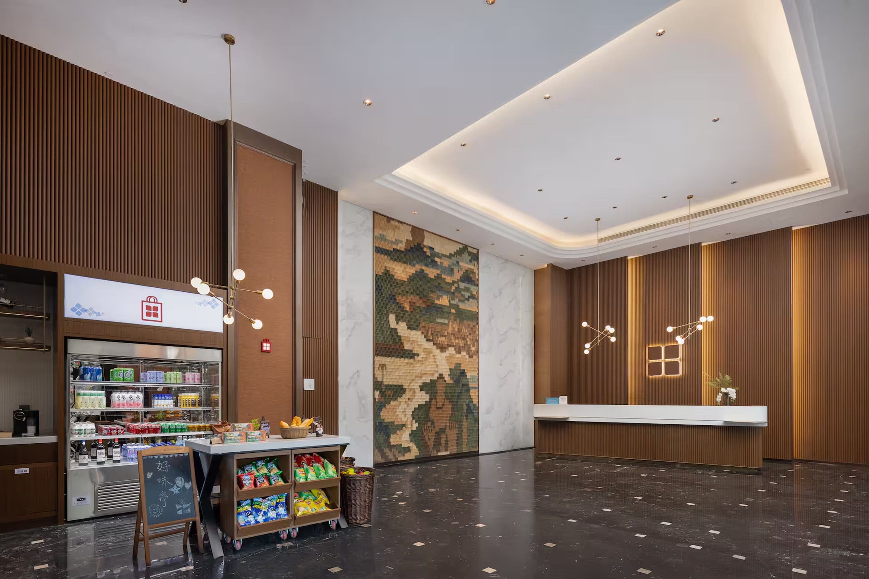 A modern hotel lobby with a reception desk, a beverage kiosk, and a large camouflage-patterned wall.