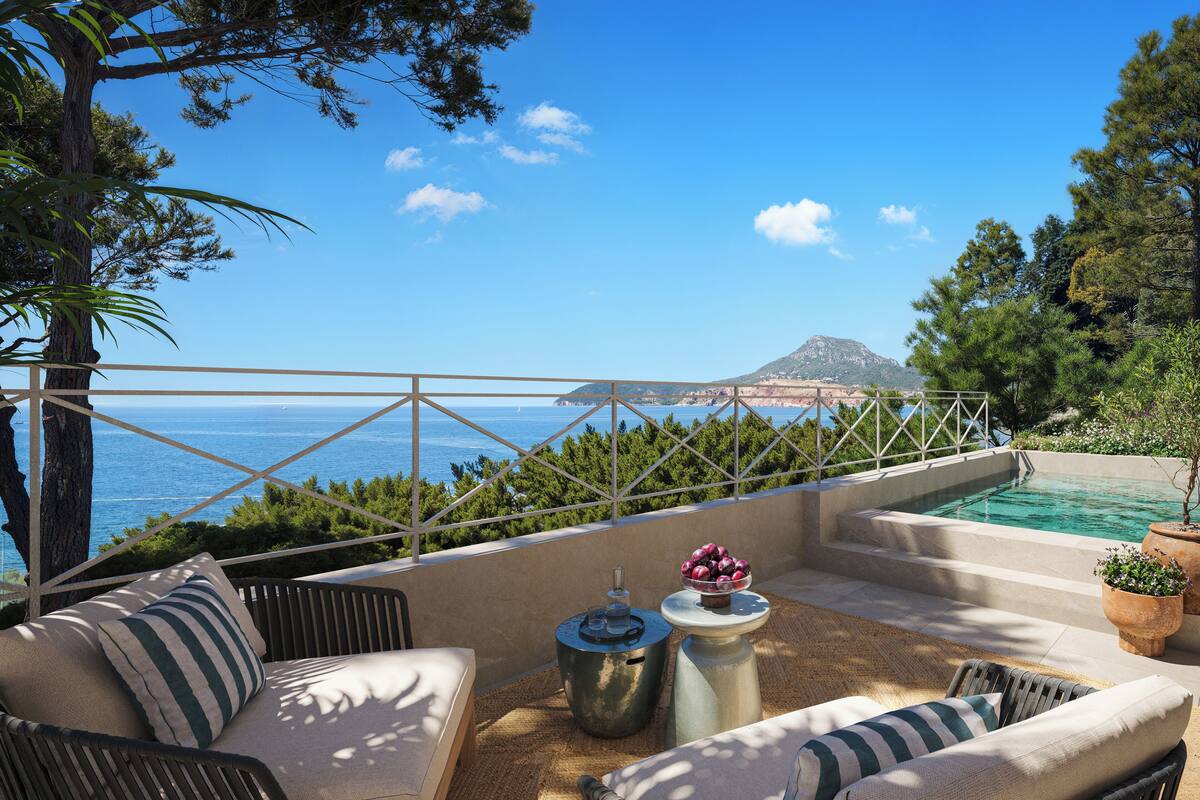 A terrace with outdoor furniture, a small pool, and a view of the sea and a mountain.