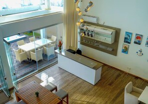 A modern interior with a reception desk, seating area, and a view to an outdoor space. - Hikka House - Thema Collection (Hikkaduwa)