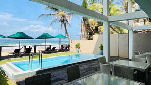 A pool area with lounge chairs and umbrellas, overlooking the beach and ocean. - Hikka House - Thema Collection (Hikkaduwa)