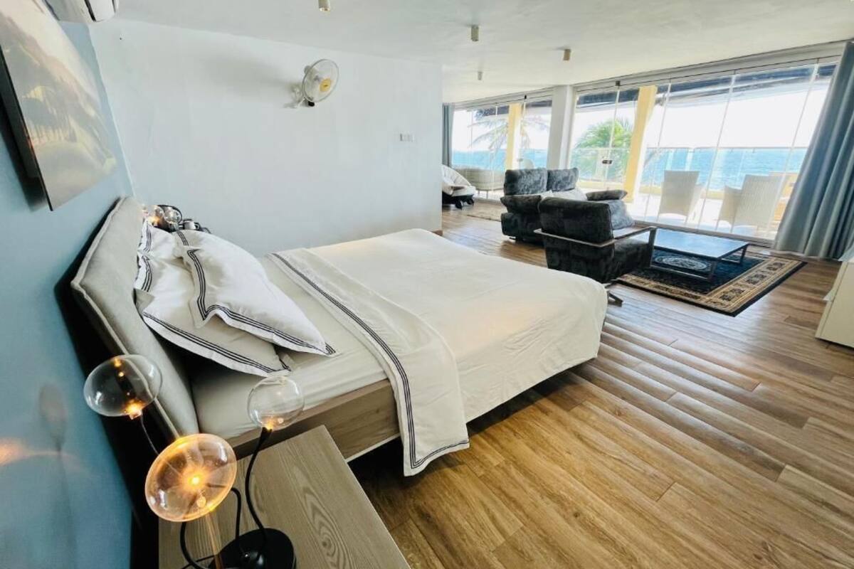 A modern hotel room with a large bed, a desk, and a view of the ocean.