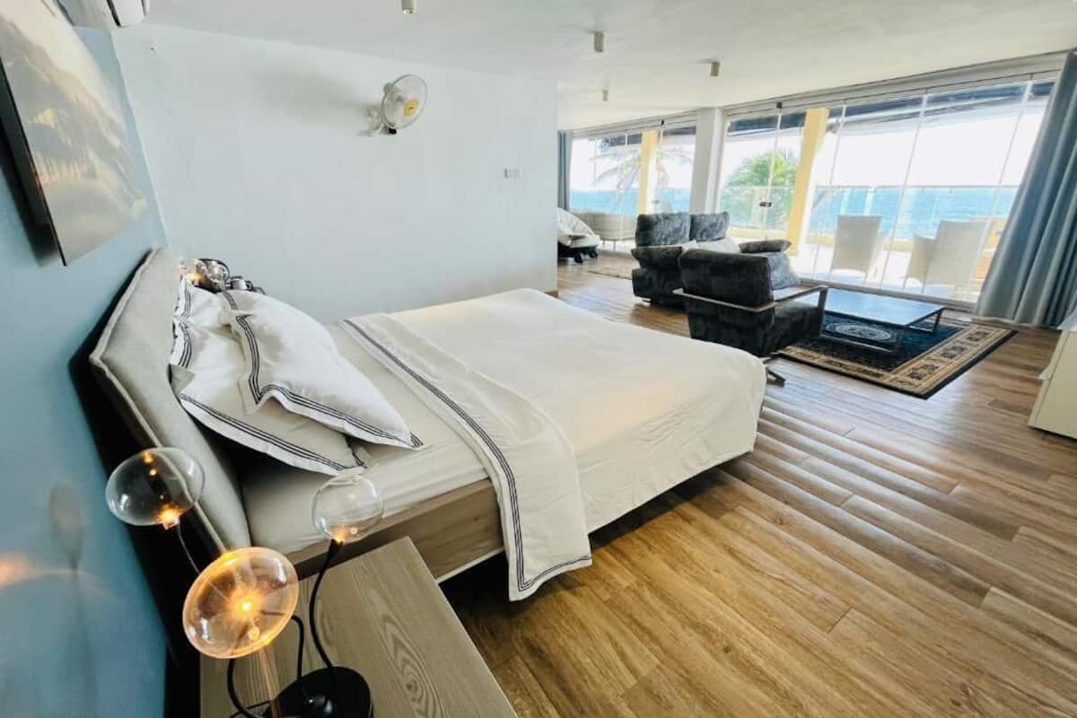 Quarto de hotel moderno com uma cama grande, uma escrivaninha e vista para o oceano.