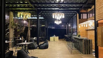 An indoor dining area with tables and chairs, a bar counter, and hanging light fixtures.