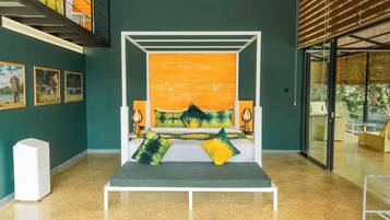 A room with a bed, artwork on the walls, and a staircase.