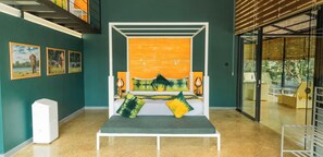 Une pièce avec un lit, des œuvres d’art accrochées aux murs et un escalier.