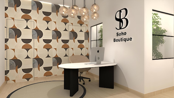 Un espace de bureau moderne avec un mur orné d’un motif géométrique, un bureau avec un ordinateur et une enseigne indiquant « Soho Boutique ».