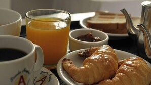 Ein Frühstückstisch mit Croissants, Orangensaft, Kaffee und einer Teekanne.
