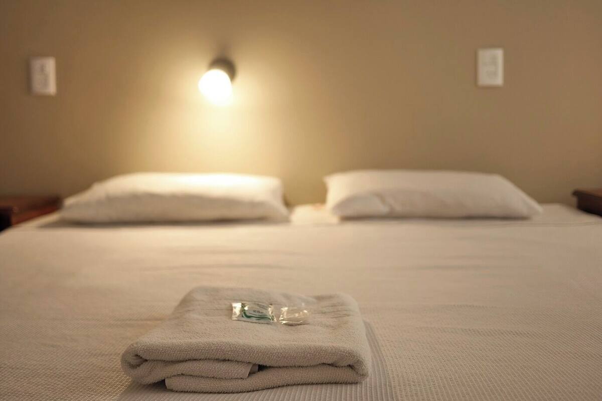 A neatly made bed with white linens and a folded towel on the bed.