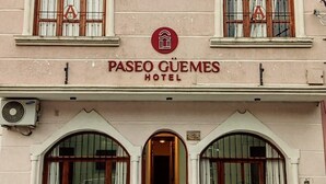 A hotel facade with multiple arched windows, a central logo, and the name 'Paseo Cuem és Hotel' displayed prominently. - Paseo Guemes Hotel (Salta)
