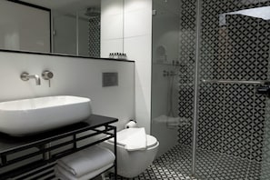 Een moderne badkamer met een groot wit wastafel, toilet en een douchecabine met glazen wanden.