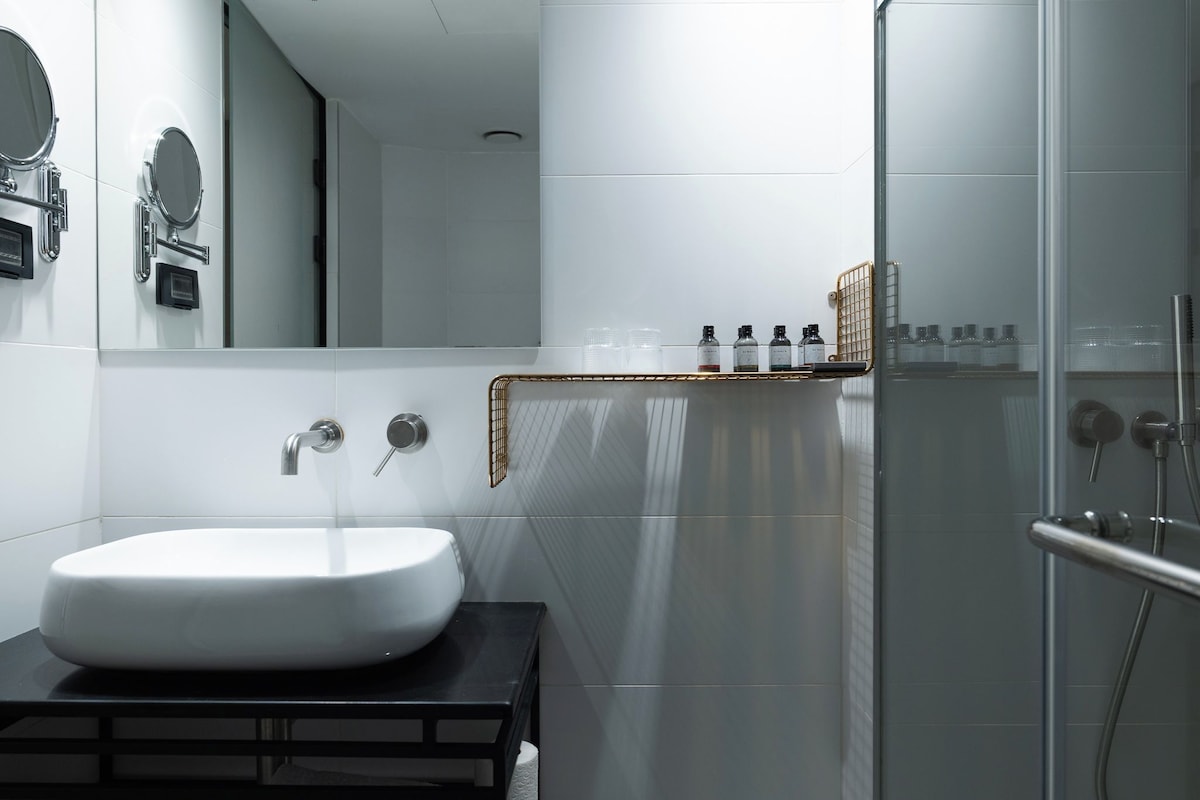 Een moderne badkamer met een witte wasbak, een spiegel en een douchecabine van glas.
