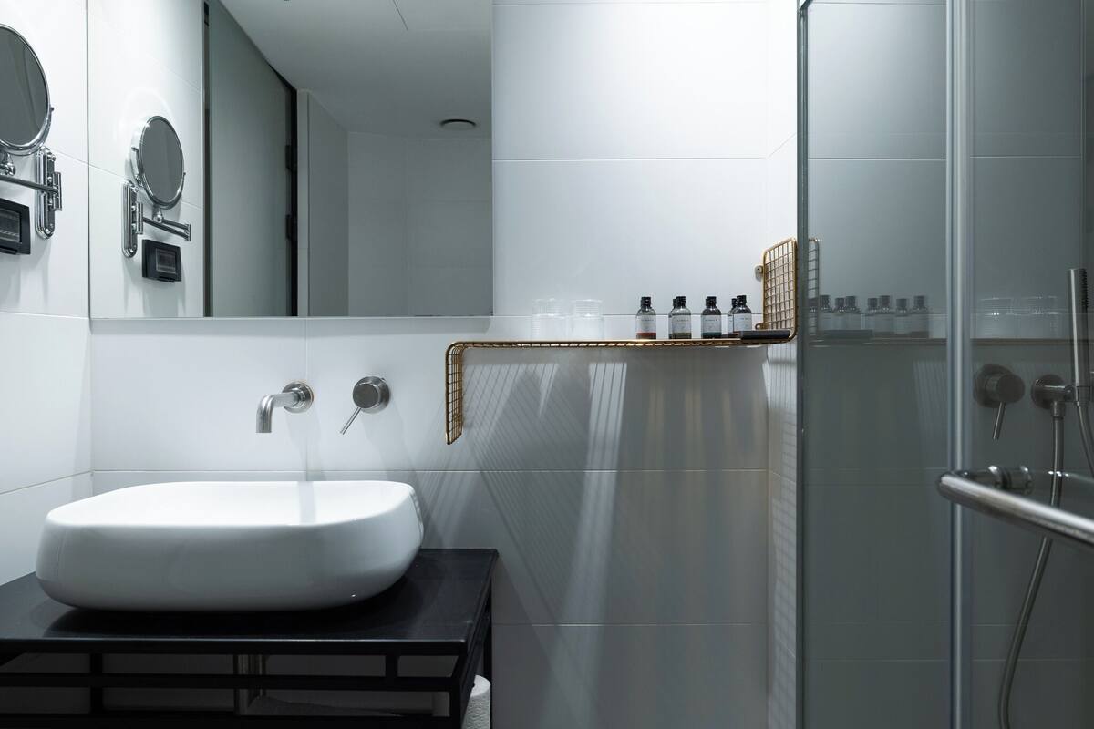 Ein modernes Badezimmer mit einem weißen Waschbecken, einem Spiegel und einer Duschkabine aus Glas.