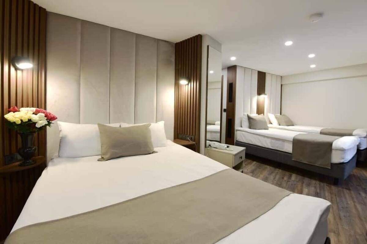 Ein modernes Hotelzimmer mit einem großen Bett, einem Nachttisch, einem Spiegel und einer kleinen Sitzecke mit einer Couch.