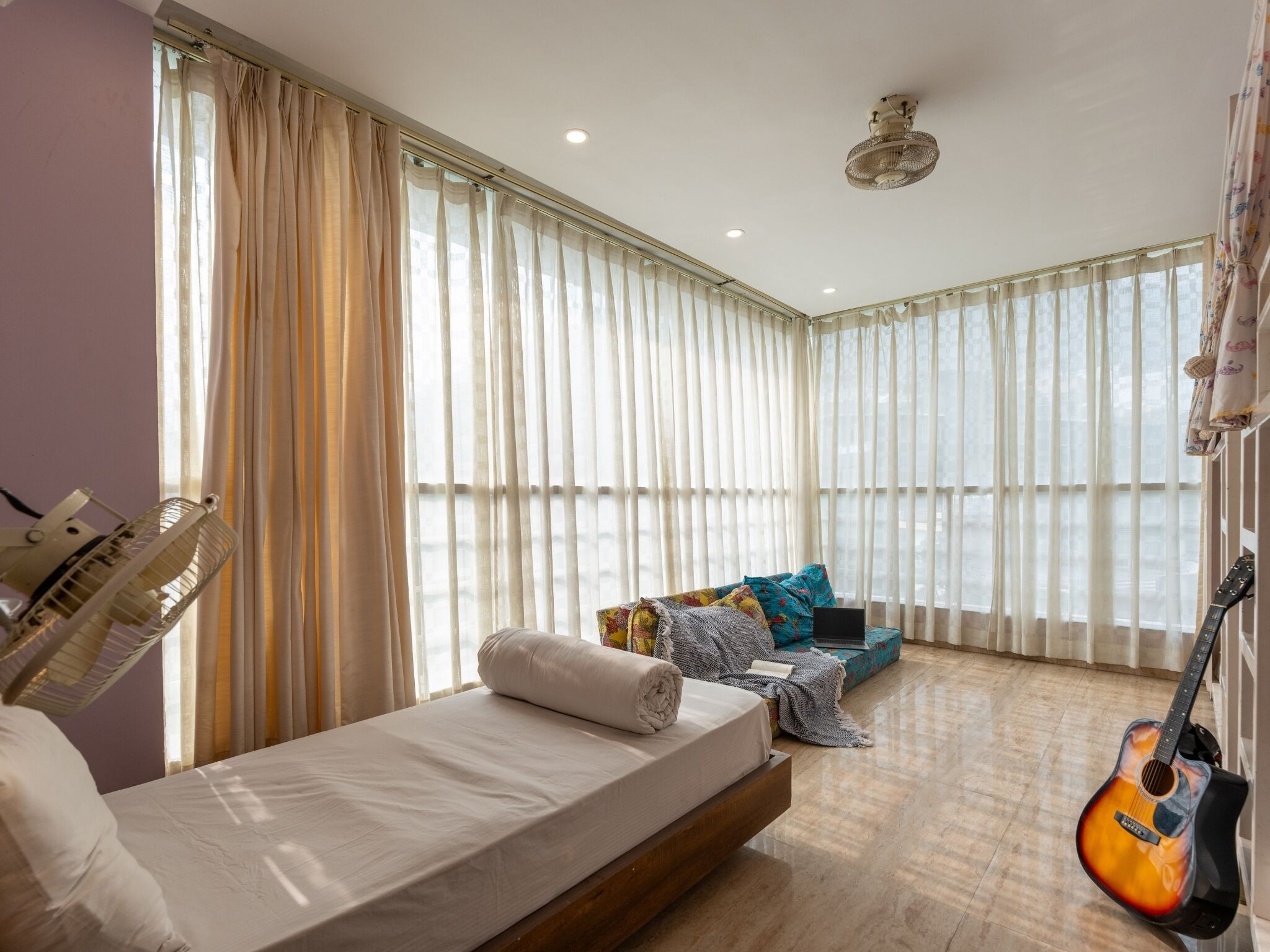 A bedroom with a bed, a guitar, and a couch.