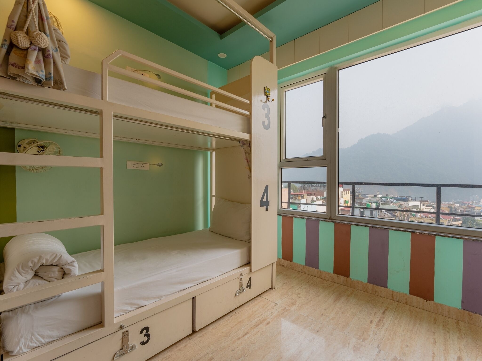 A bunk bed room with a view of a city and mountains.
